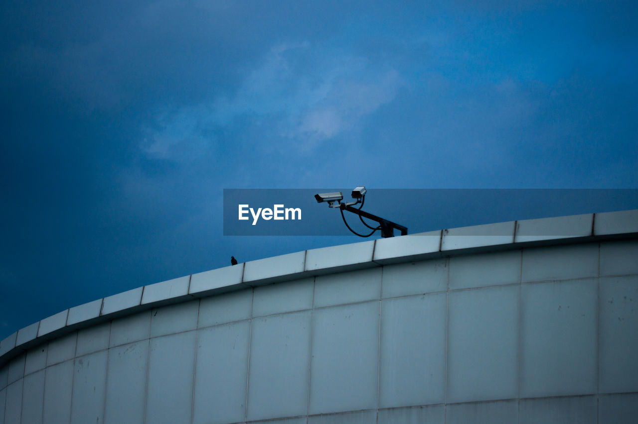 Low angle view of man climbing on building against sky