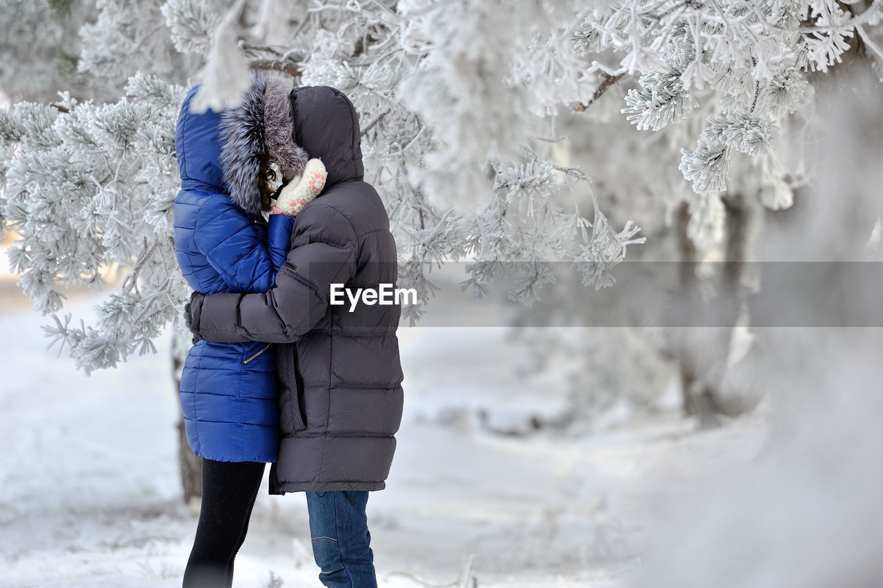 Side view of couple hugging in the snow