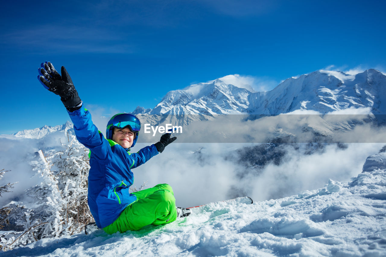 full length of man standing on snowcapped mountains against blue sky