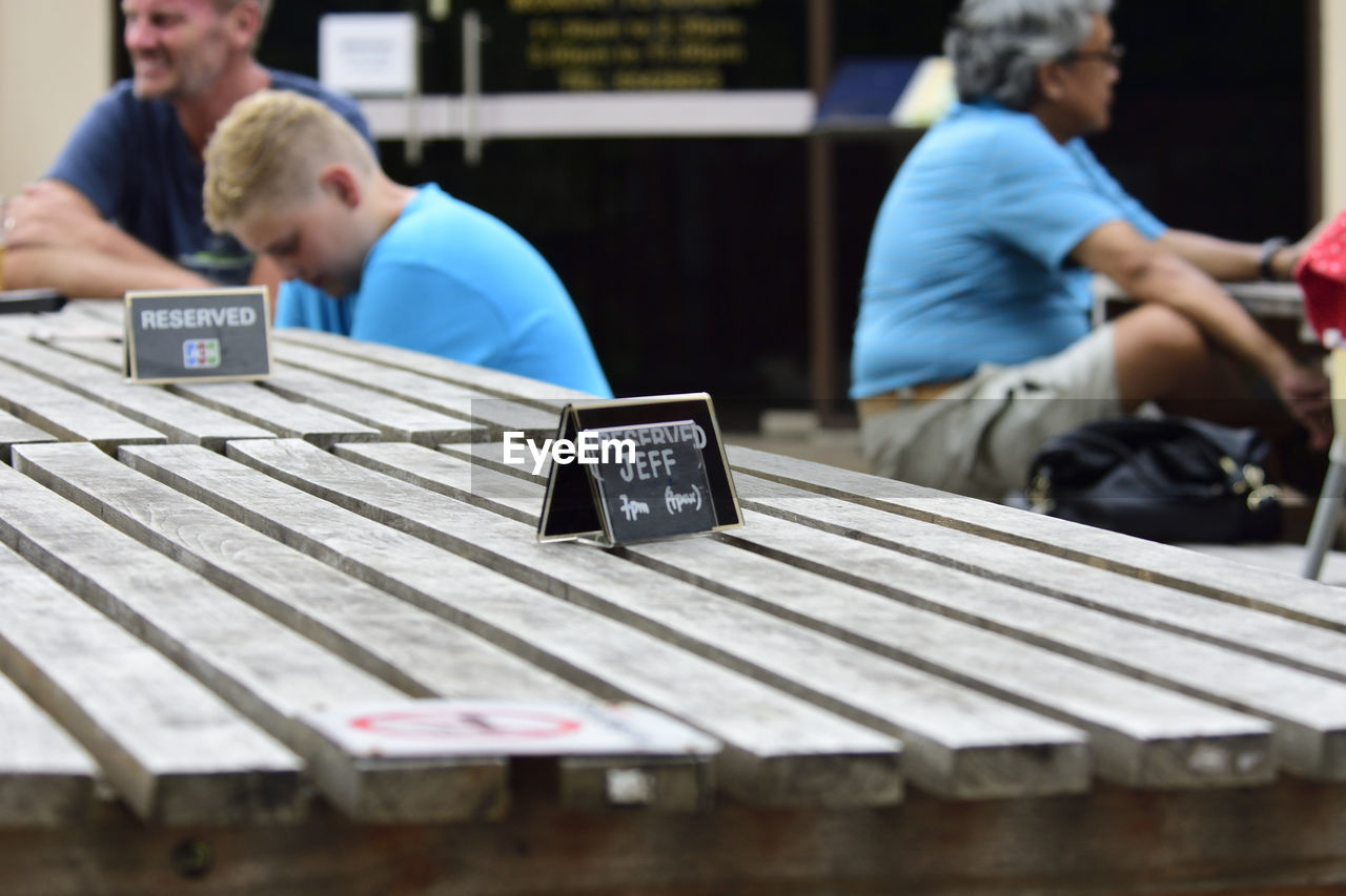 Close-up of label on table with people in background