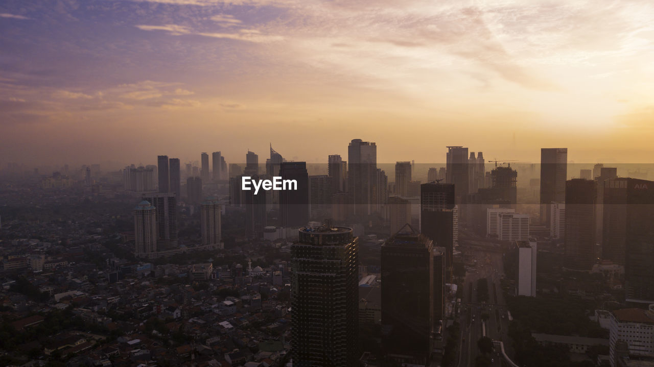 Aerial view of modern buildings against sky during sunset