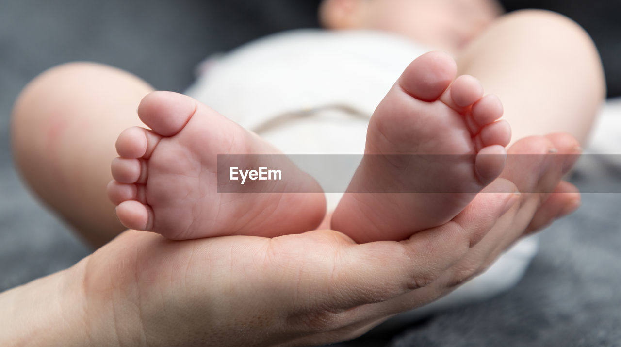 Close-up of cropped mother holding baby feet