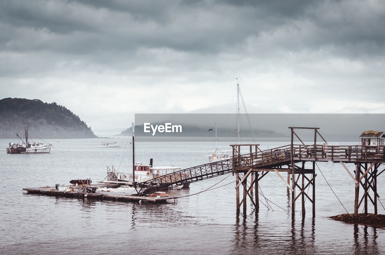 Harbor in sea against cloudy sky