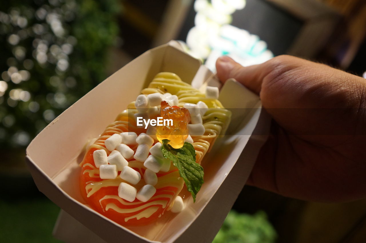 CLOSE-UP OF HAND HOLDING CAKE