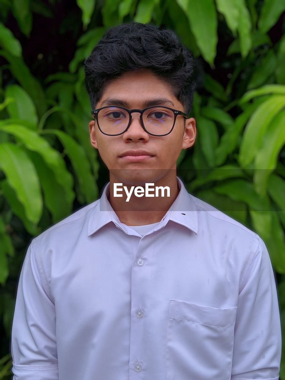 Portrait of teenage boy in eyeglasses standing outdoors