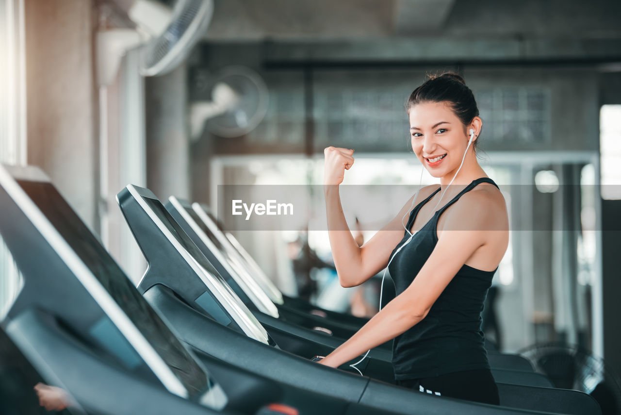 Portrait of woman smiling while exercising on treadmill at gym
