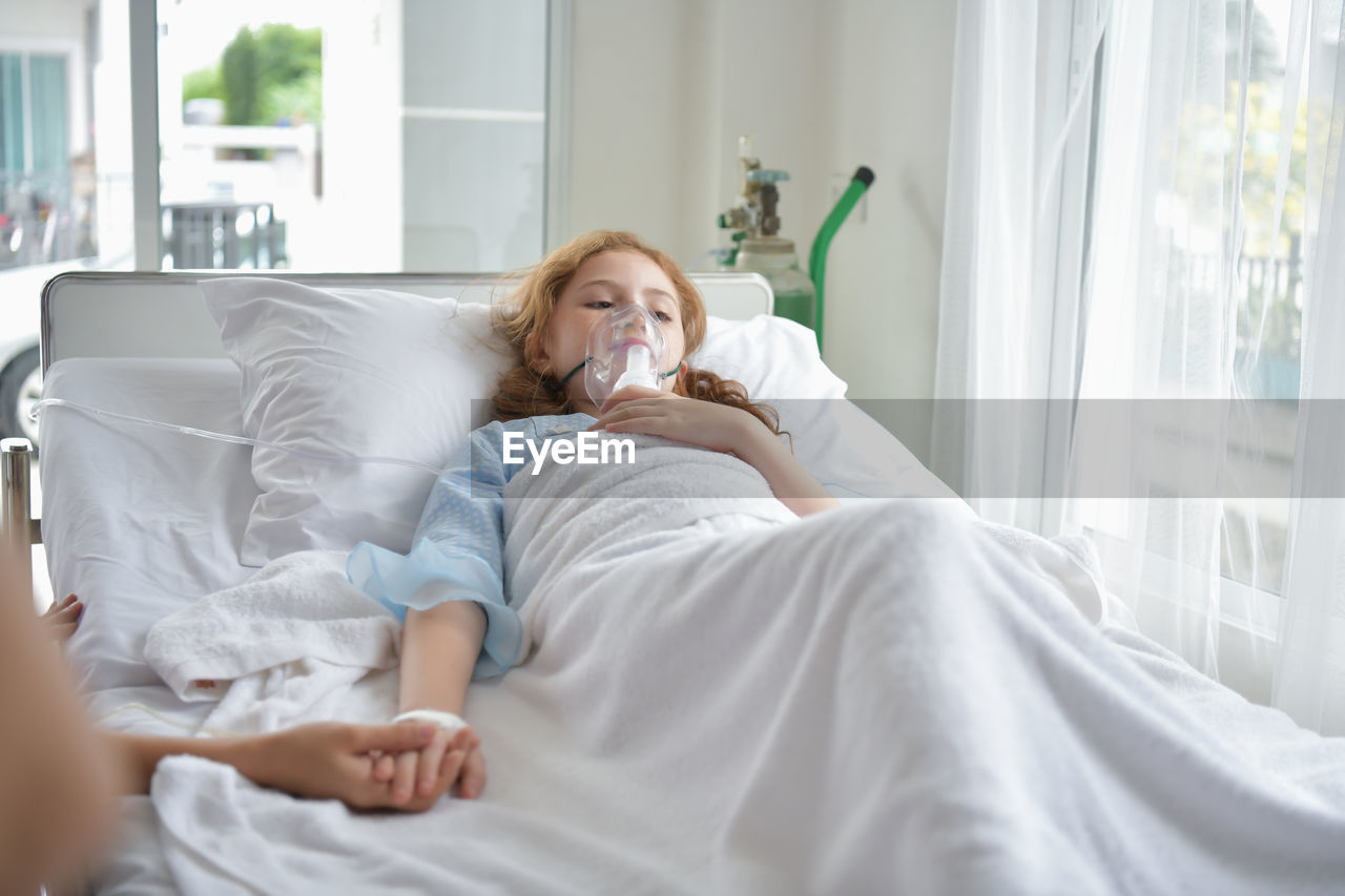 Girl with oxygen mask on bed at hospital