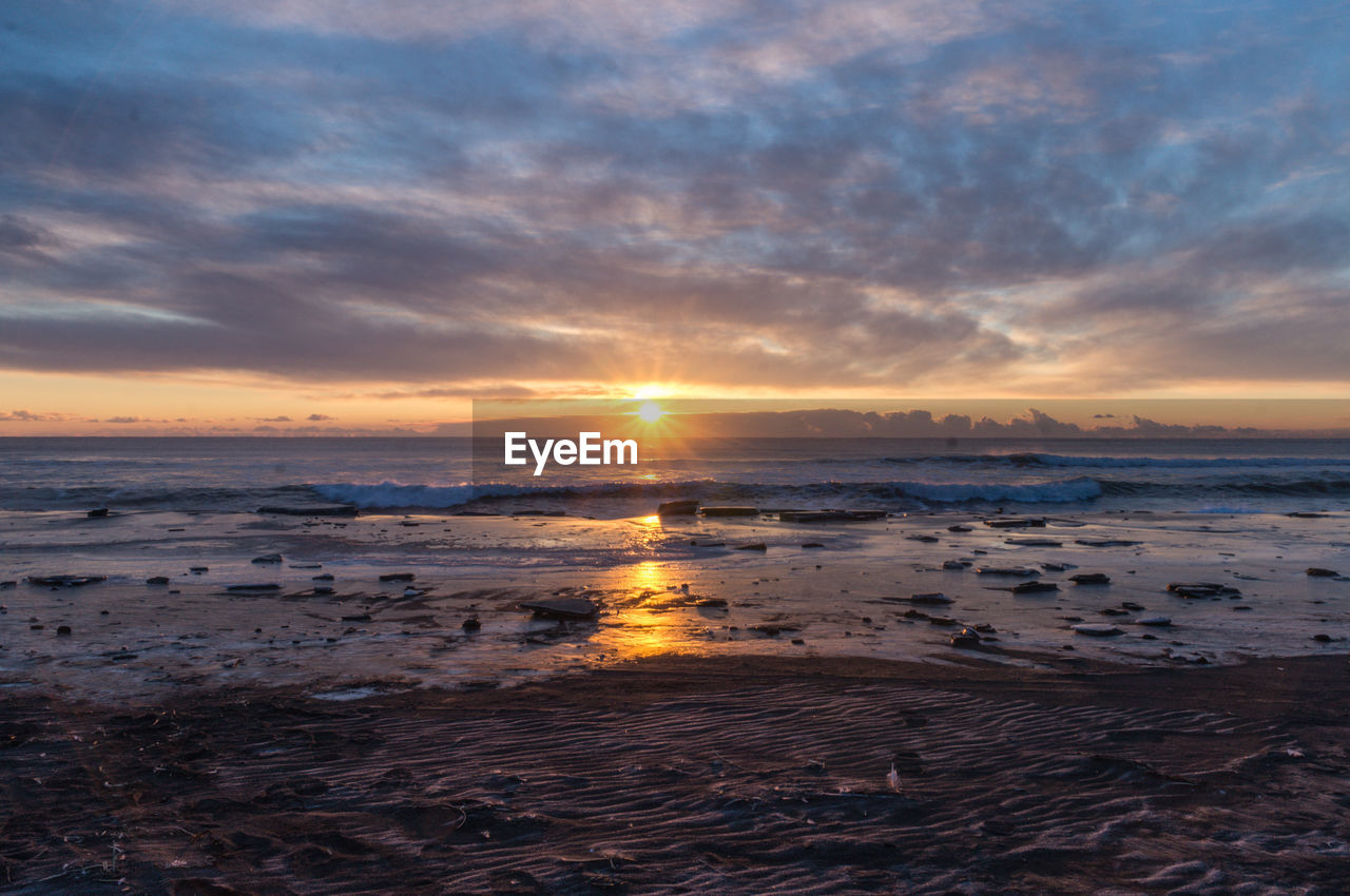 Scenic view of sea against dramatic sky during sunset