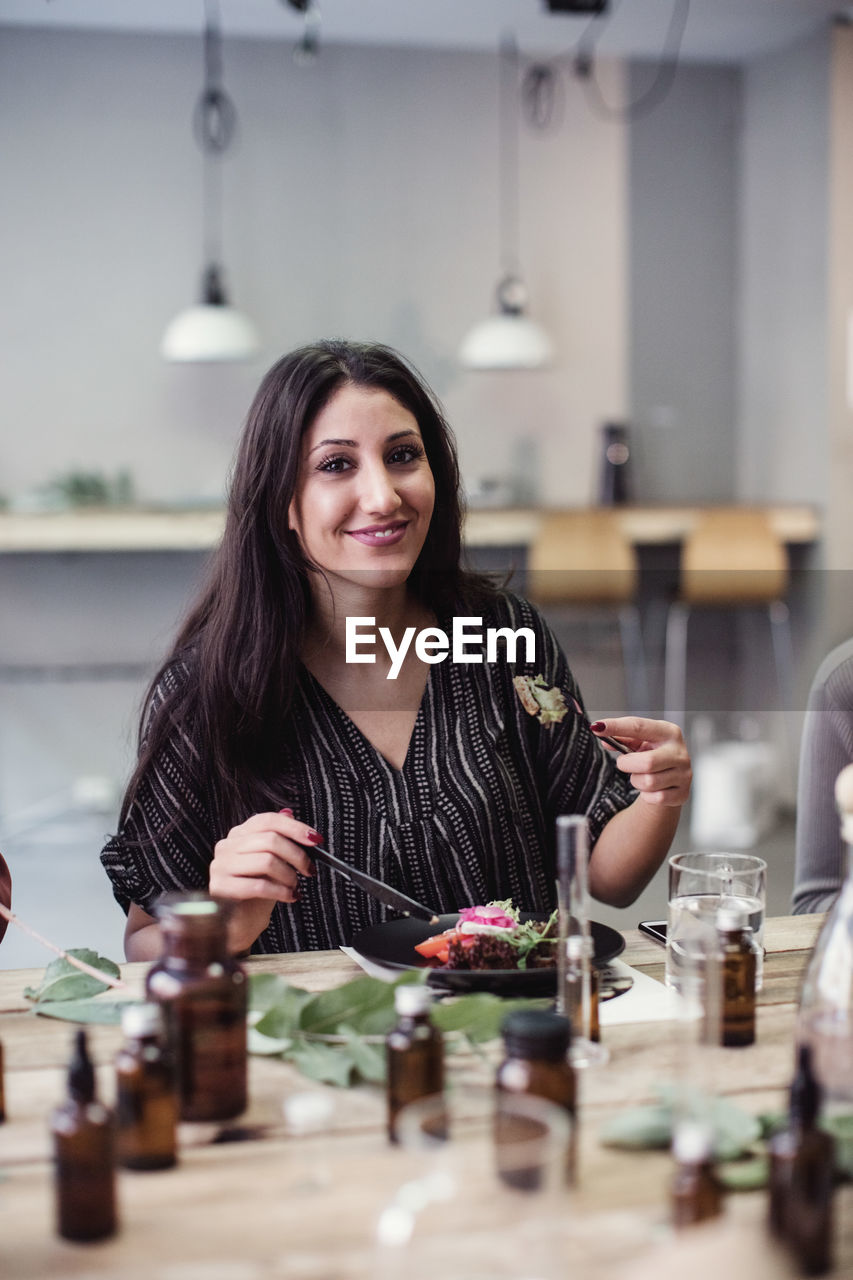 Portrait of smiling young woman eating lunch at perfume workshop