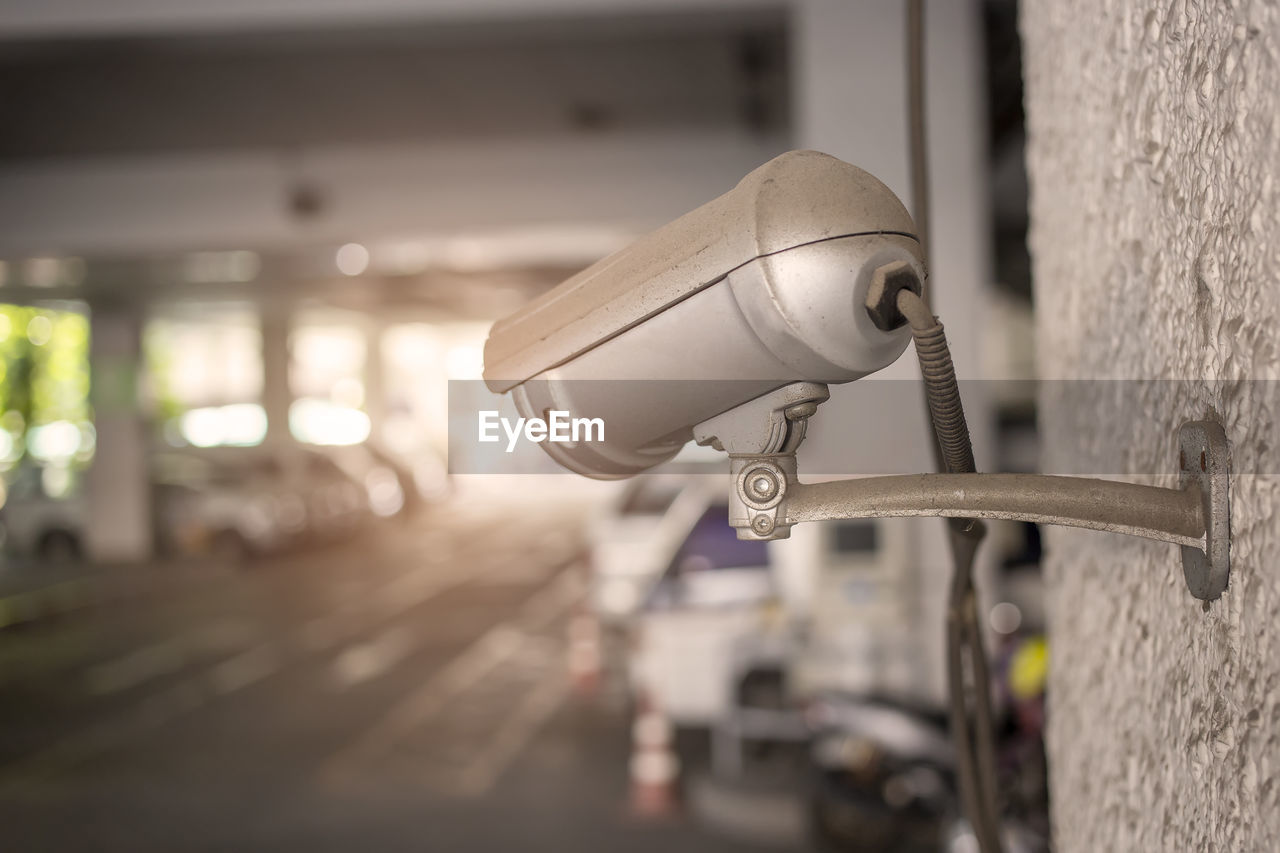 Close-up of surveillance camera on wall at parking lot