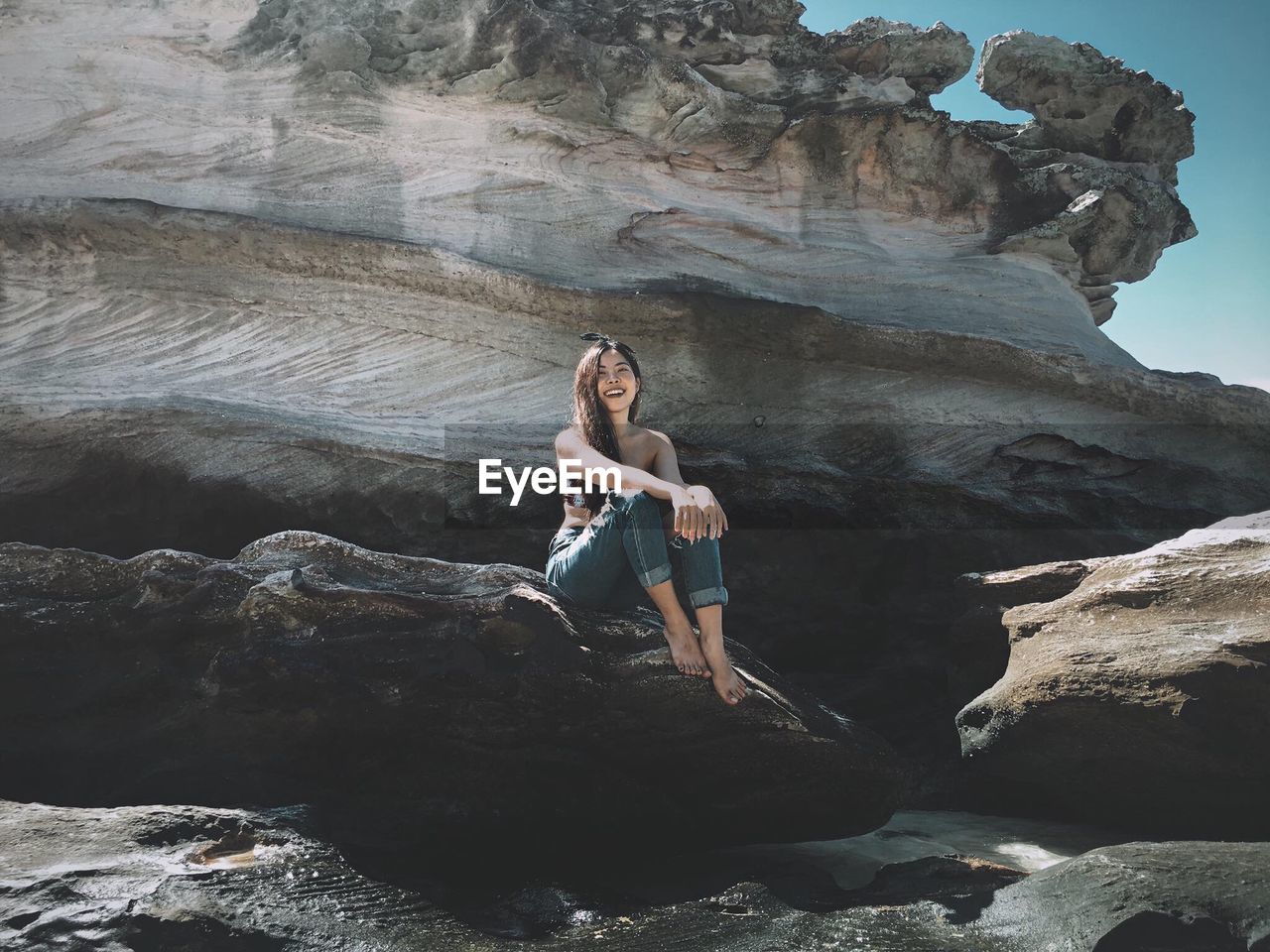 Full length of woman sitting on rock at beach