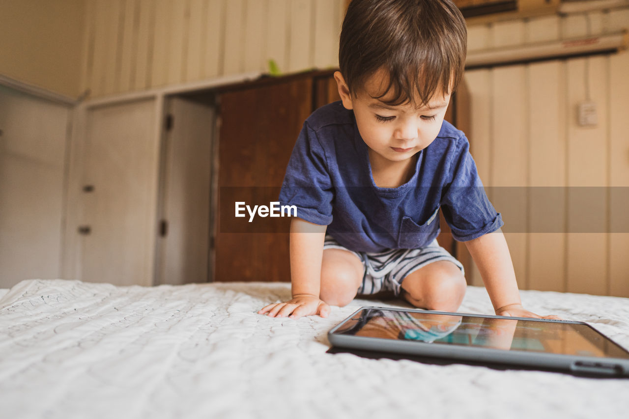 Boy looking at camera while sitting on bed