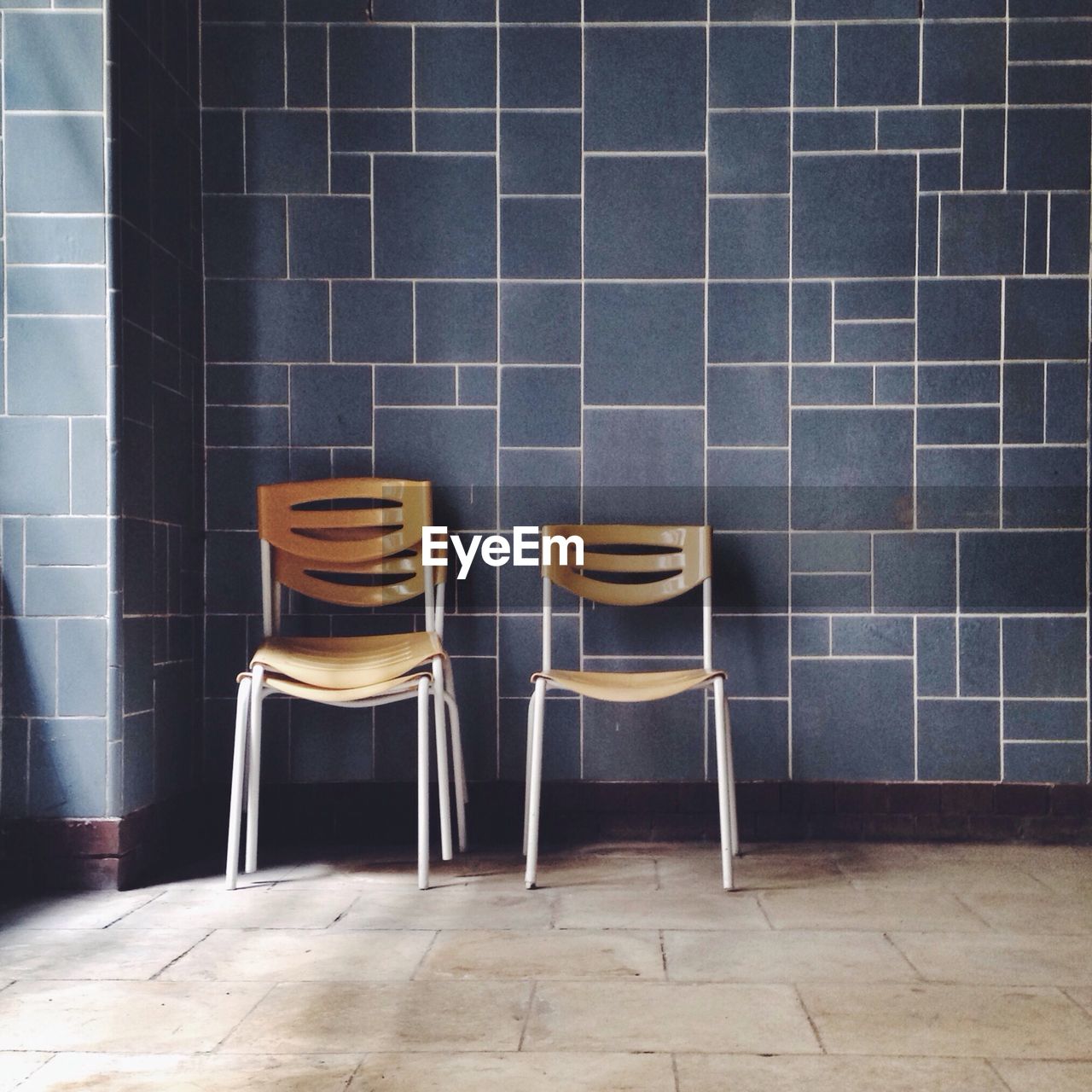 Empty chairs against tiled wall