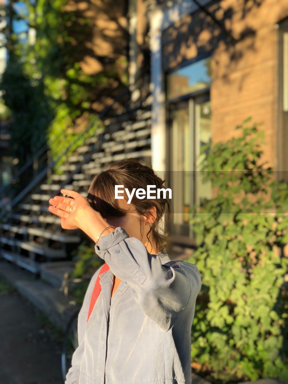 Woman shielding eyes while standing outdoors