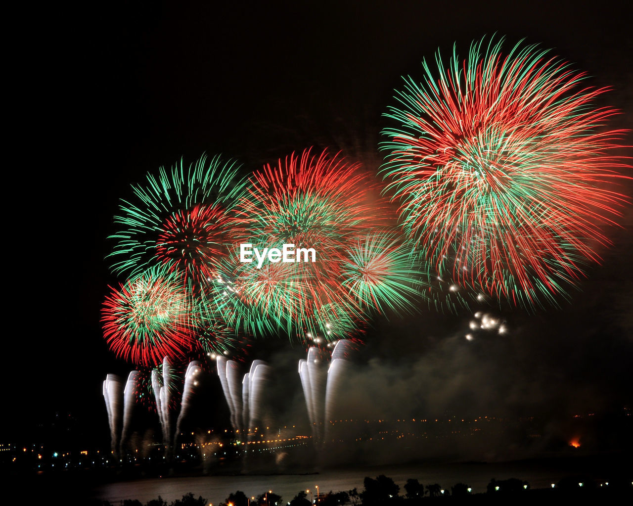 Firework display over river in illuminated city at night