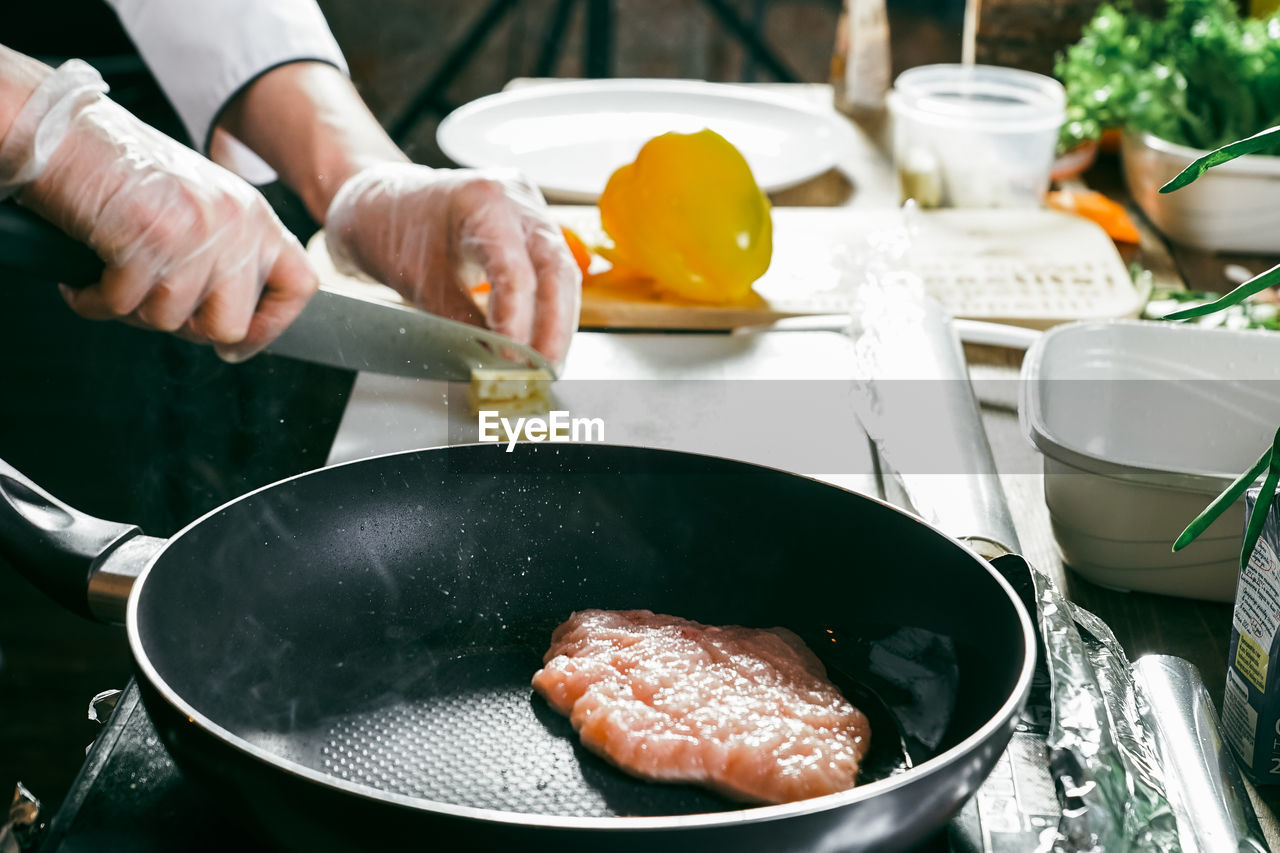 MIDSECTION OF MAN PREPARING MEAT IN KITCHEN