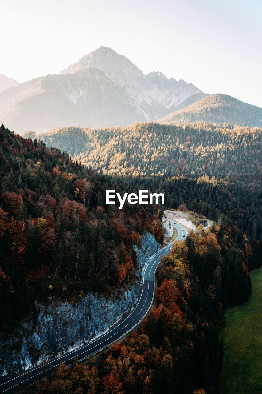 Aerial view of road amidst trees against mountains during autumn