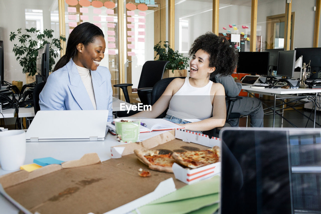 Happy businesswomen laughing while sitting at office