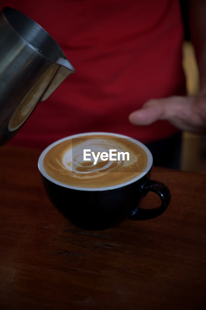 Midsection of woman holding coffee on table