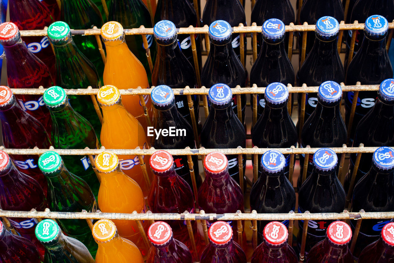 FULL FRAME SHOT OF MULTI COLORED BOTTLES ON RACK