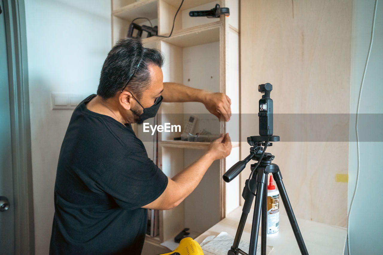 Man diy wood project at home. camera recording on the tripod.