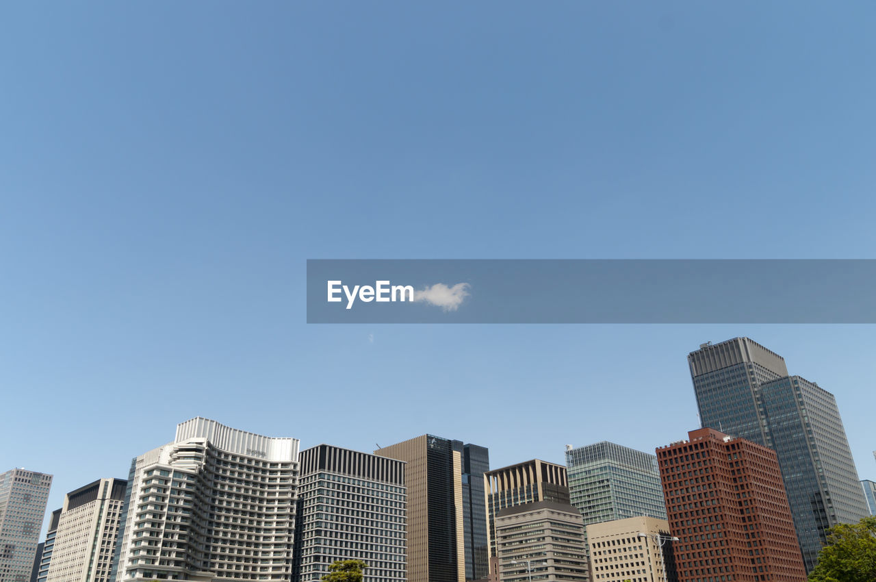 Low angle view of buildings in city against blue sky