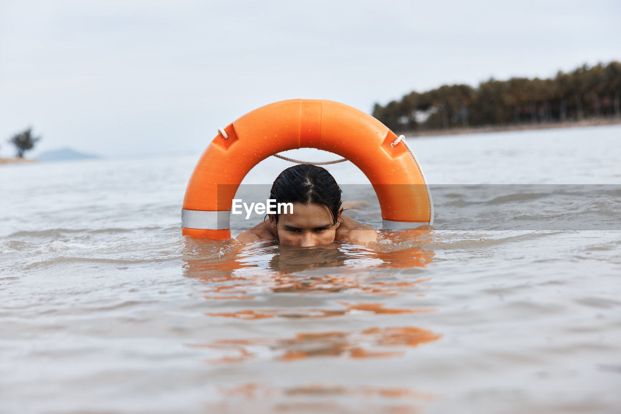 portrait of shirtless man swimming in lake