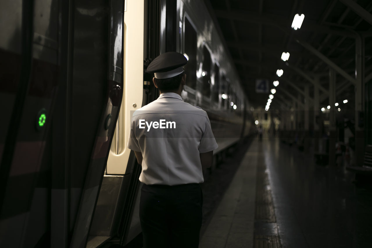 Rear view of men standing by train at railroad station platform