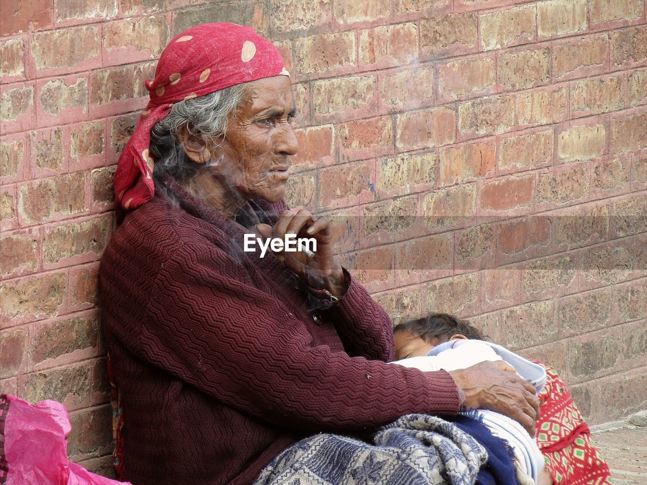 WOMAN SITTING ON BRICK WALL