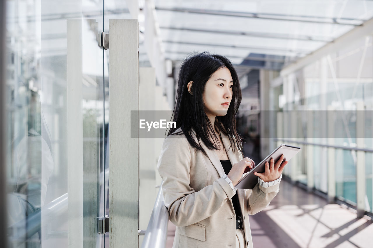 Portrait of beautiful chinese business woman using digital tablet in building office. technology