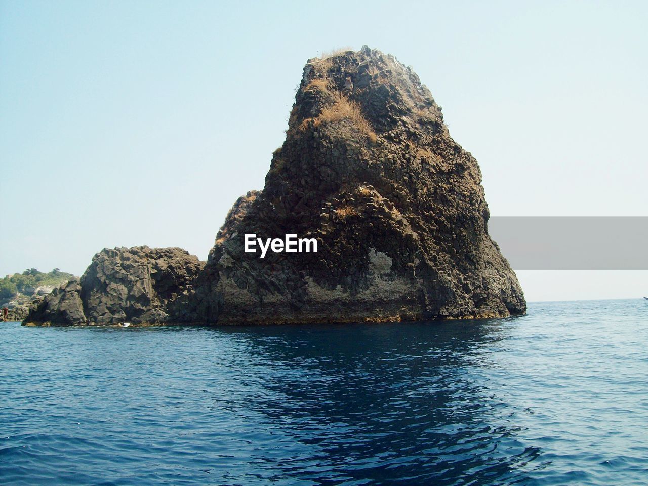 ROCK FORMATION IN SEA AGAINST BLUE SKY