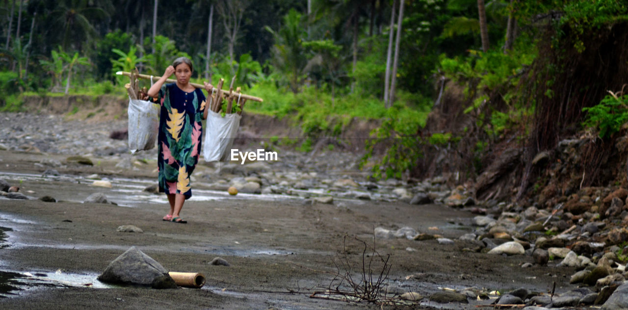 Full length of woman carrying wood on shore of beach