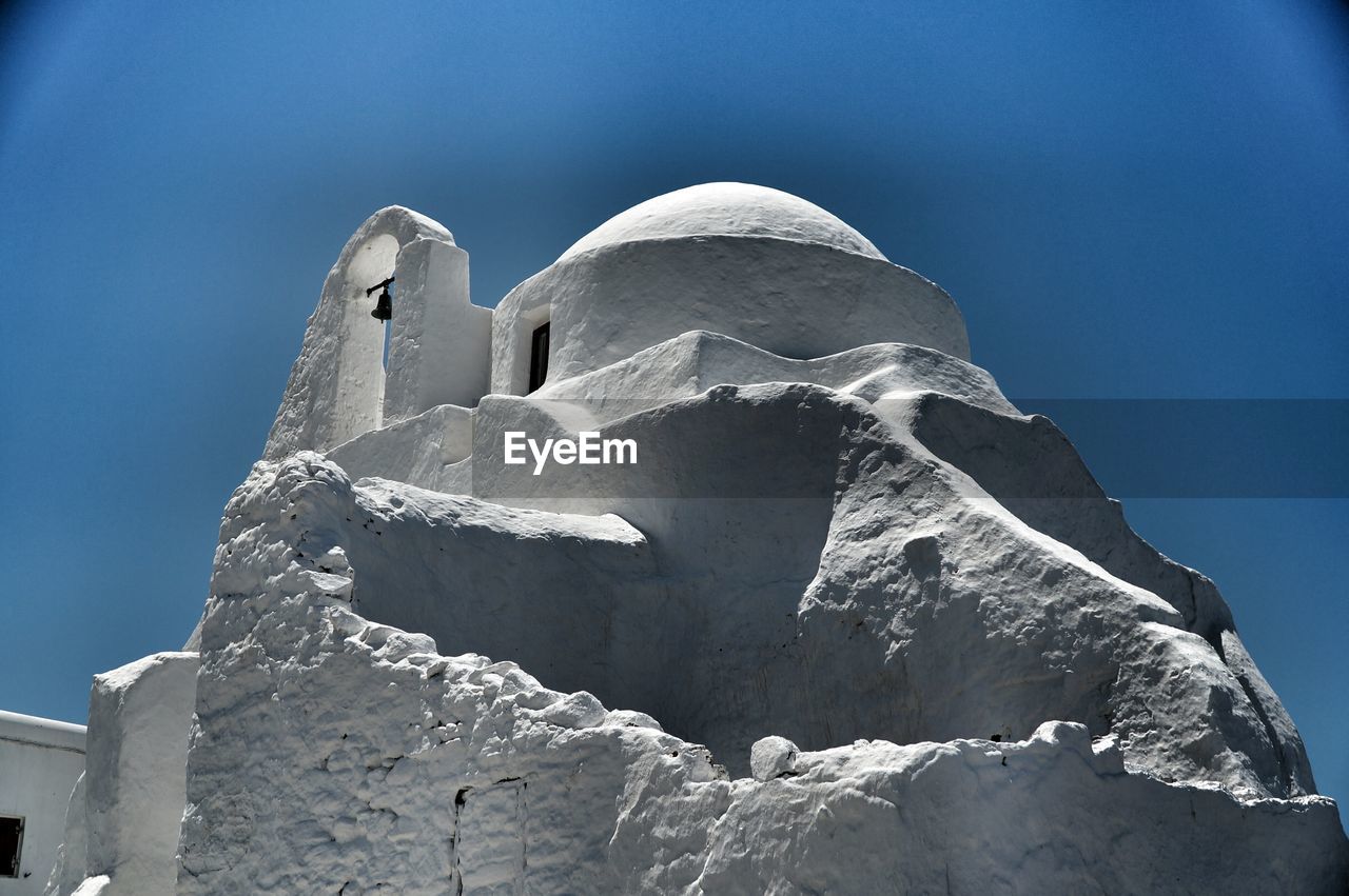 Low angle view of built structures against clear blue sky