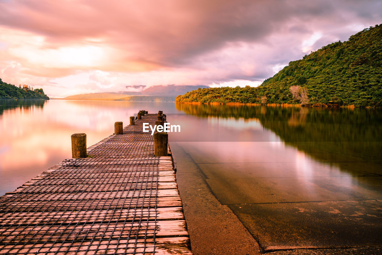 PIER OVER LAKE AGAINST SKY DURING SUNSET