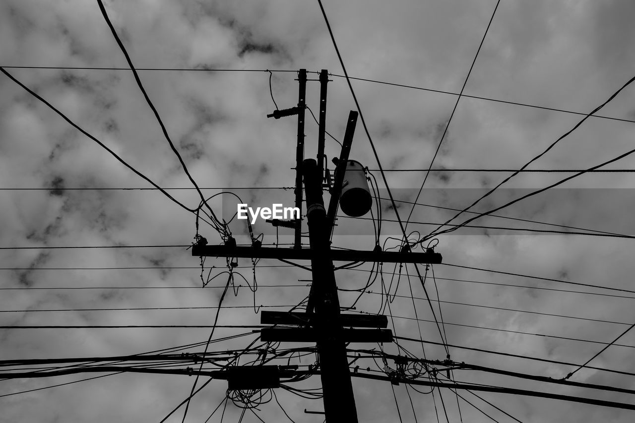 Low angle view of electricity pylon against cloudy sky