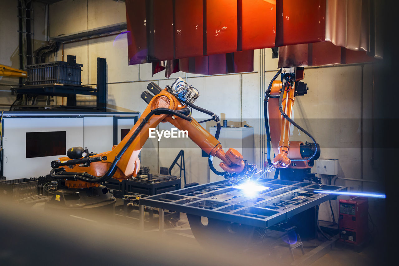 Orange robotic arms welding in industry