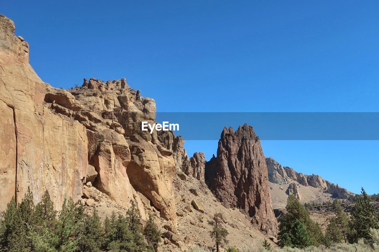 LOW ANGLE VIEW OF ROCKY MOUNTAINS AGAINST CLEAR BLUE SKY