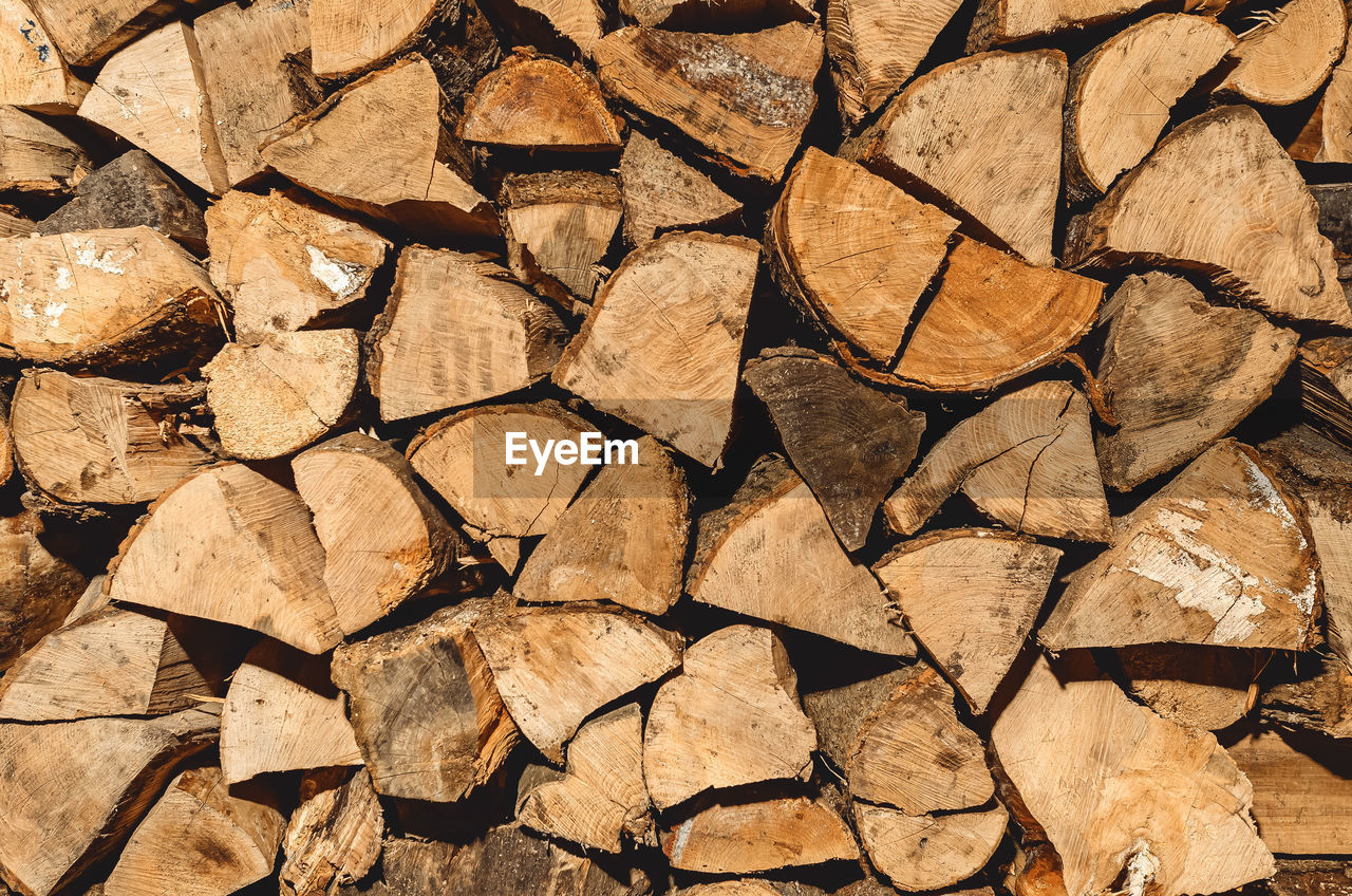 Stack of neatly stacked firewood is dried under a canopy in the open air. background for design. 