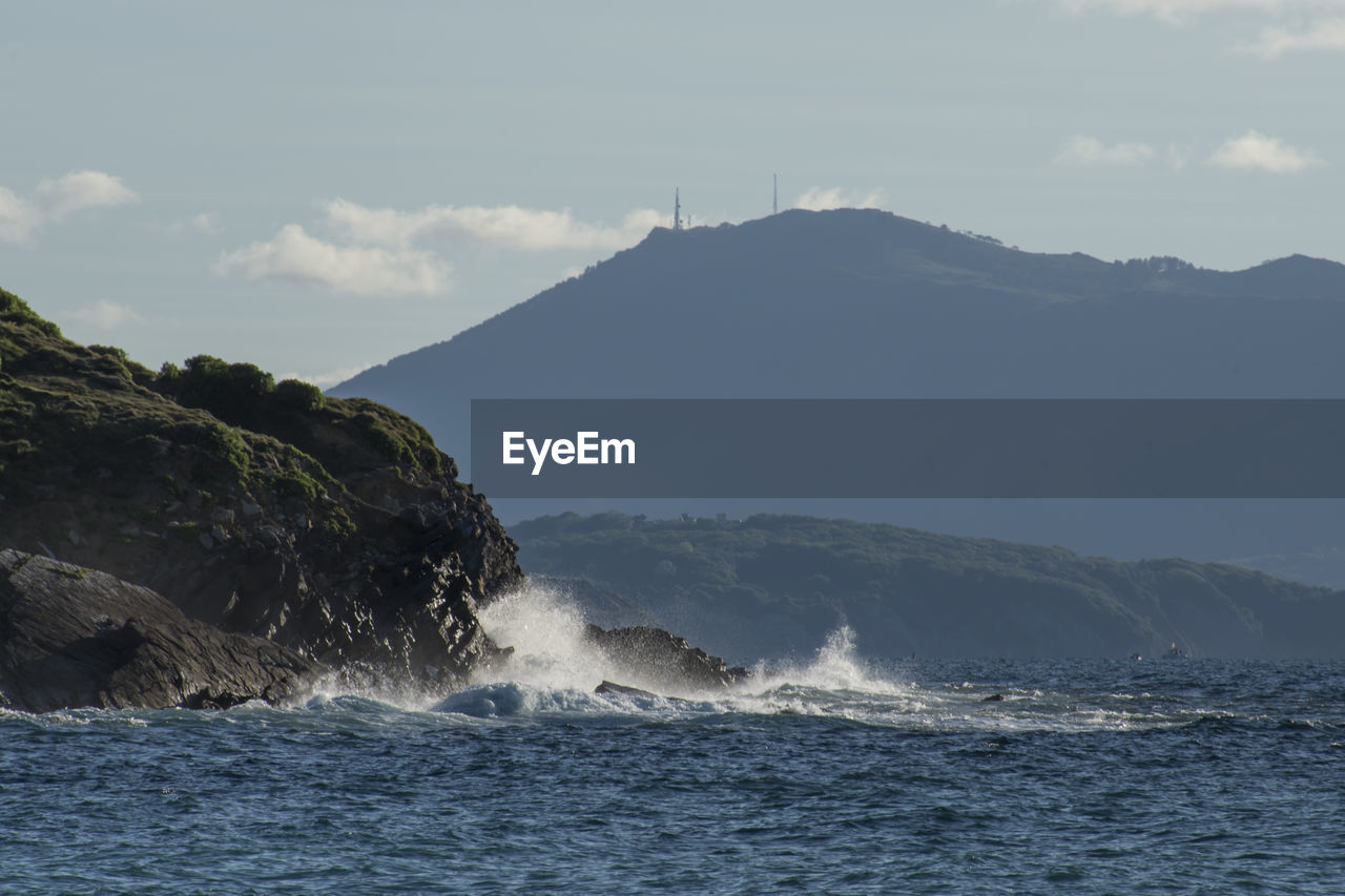 Scenic view of sea and mountains against sky