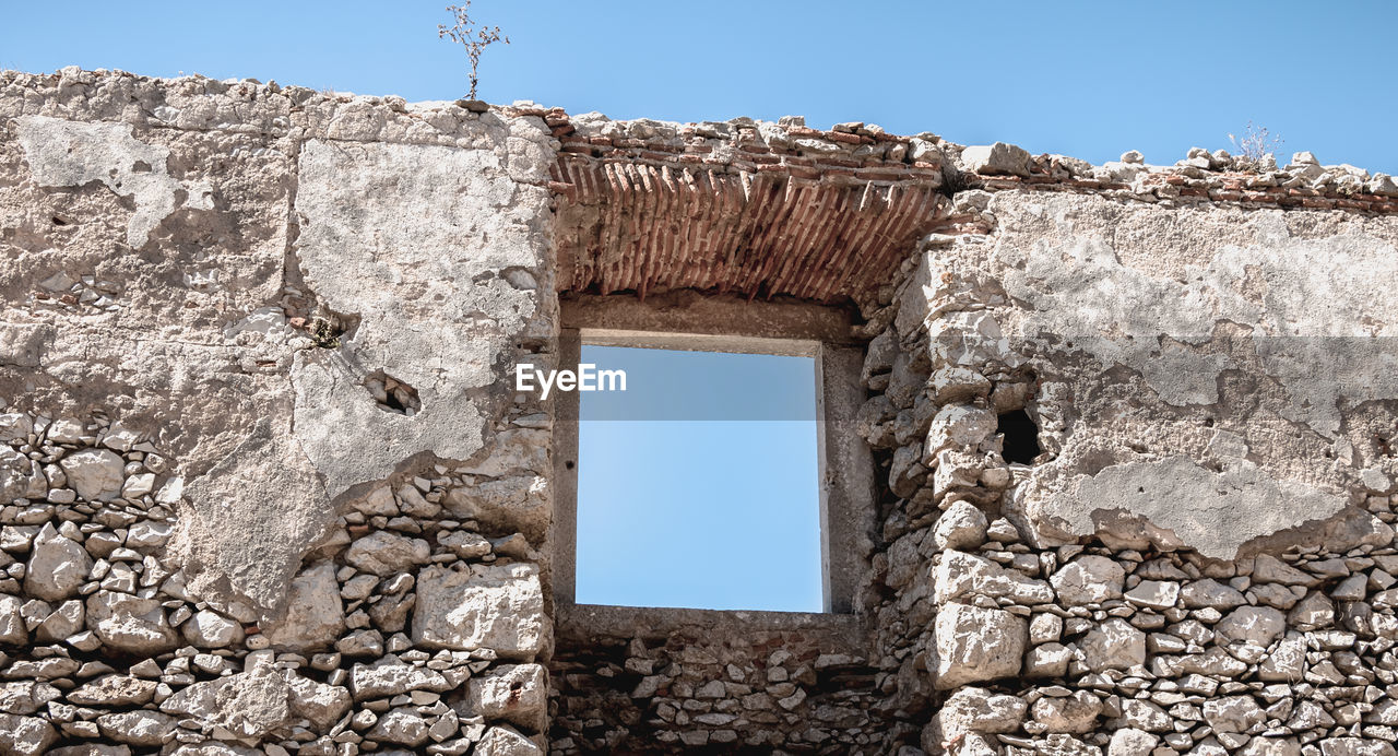 LOW ANGLE VIEW OF WALL AGAINST CLEAR SKY