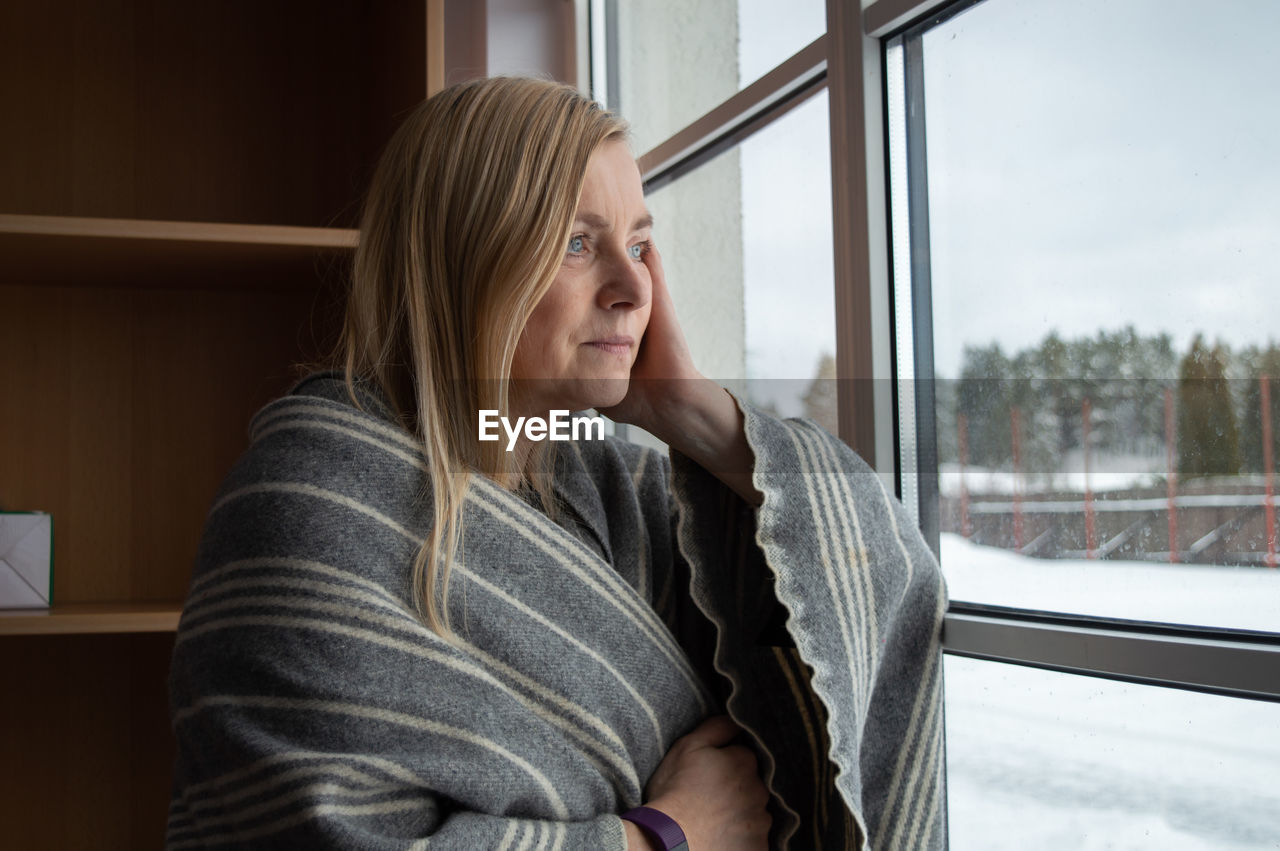 Mature woman looking through window