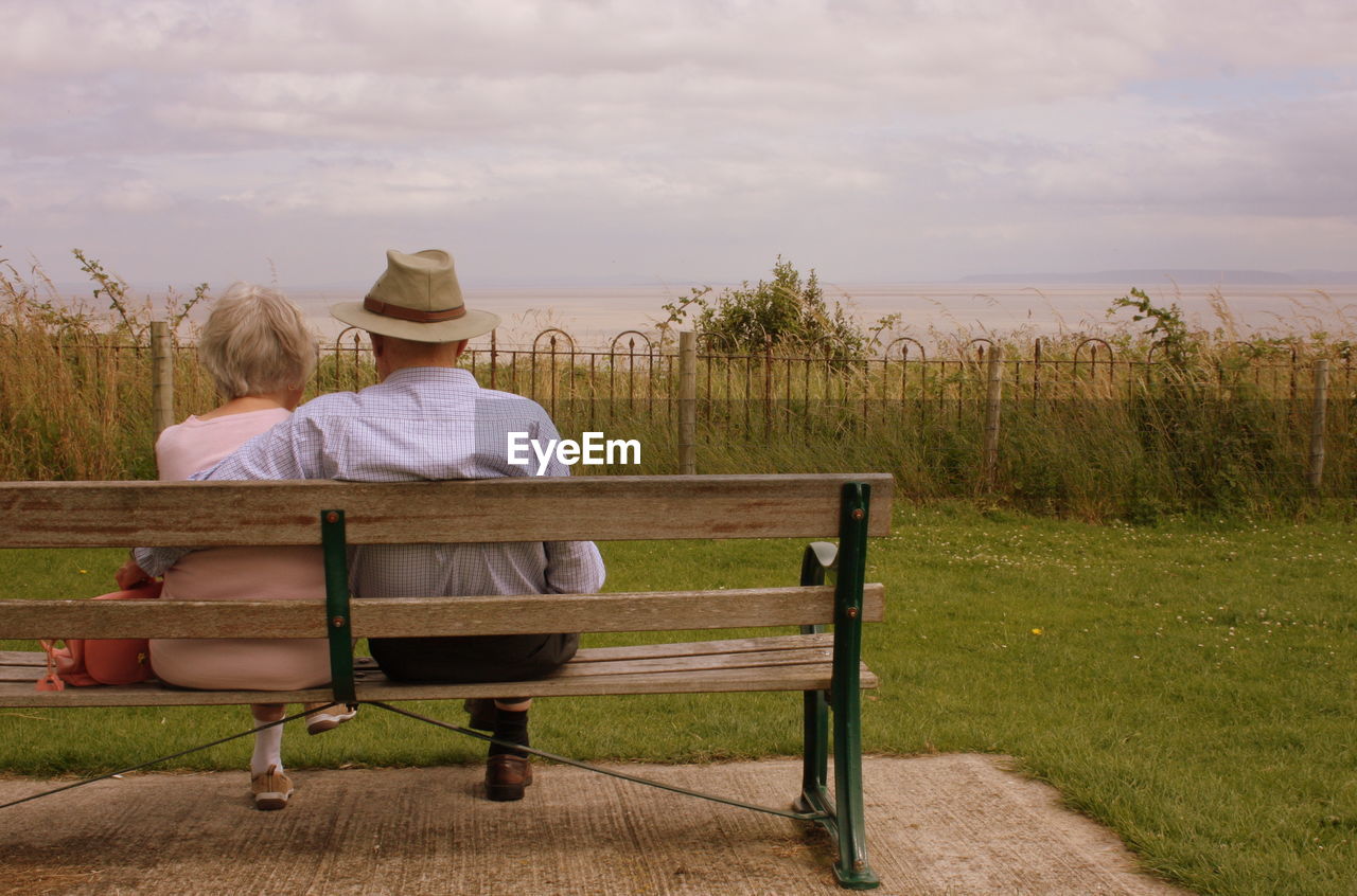 Rear view of couple sitting on bench in park