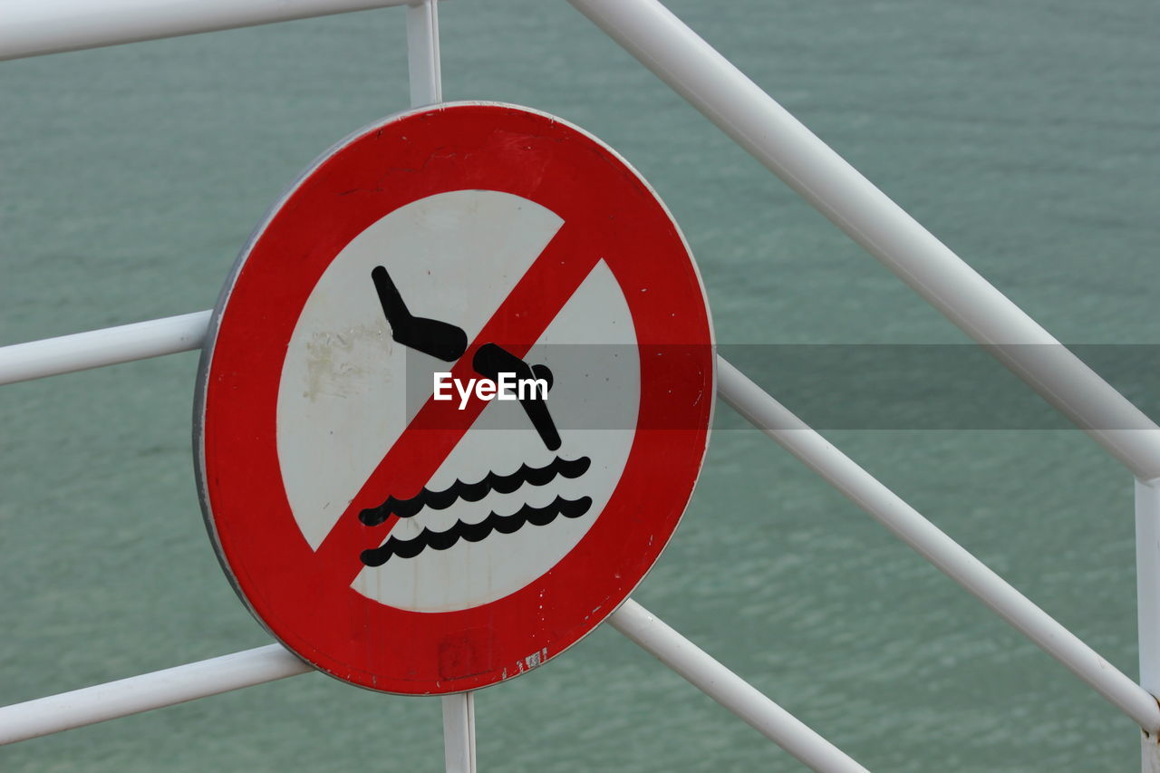 No diving sign on railing against sea