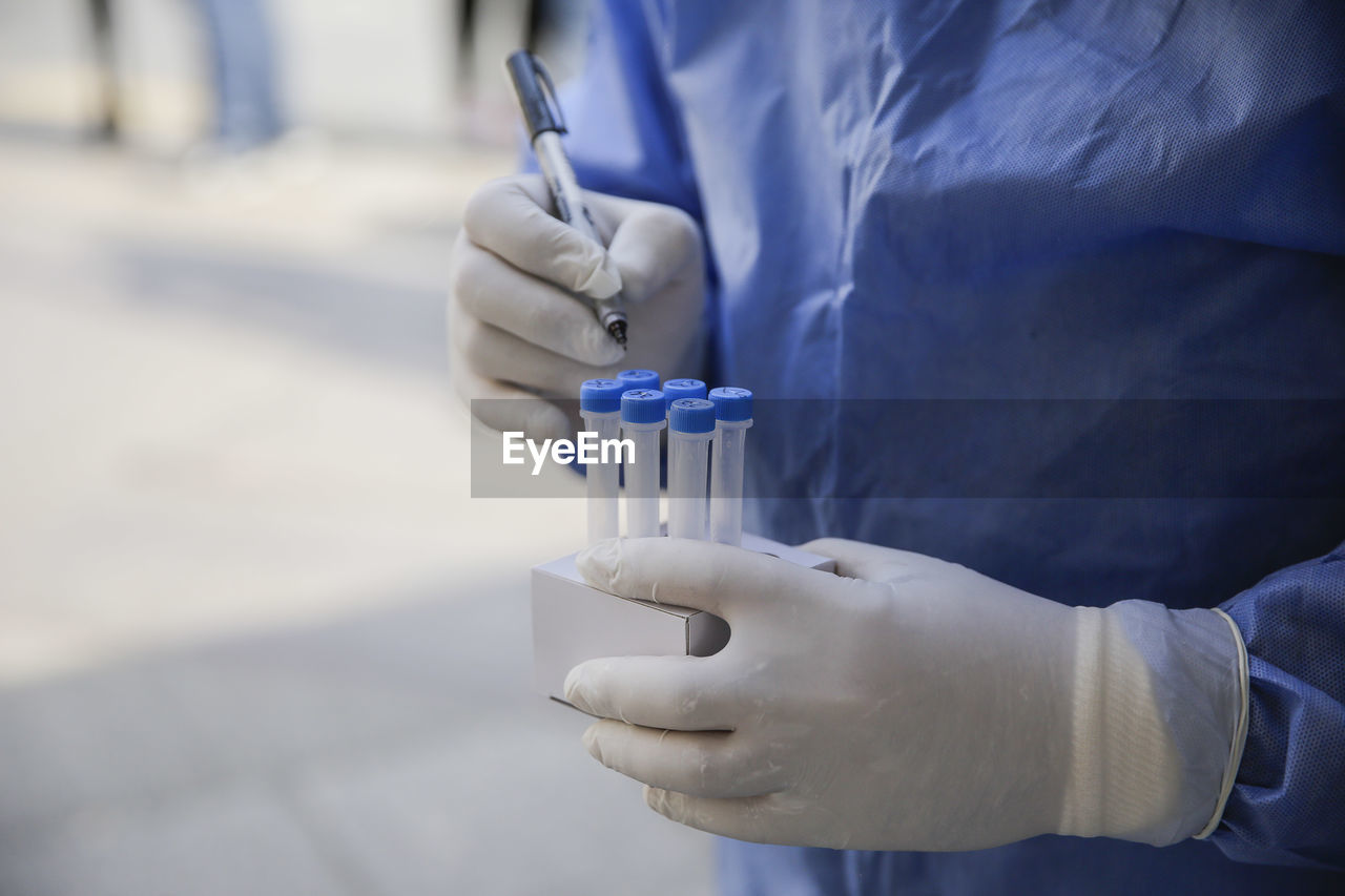 Midsection of scientist holding test tubes