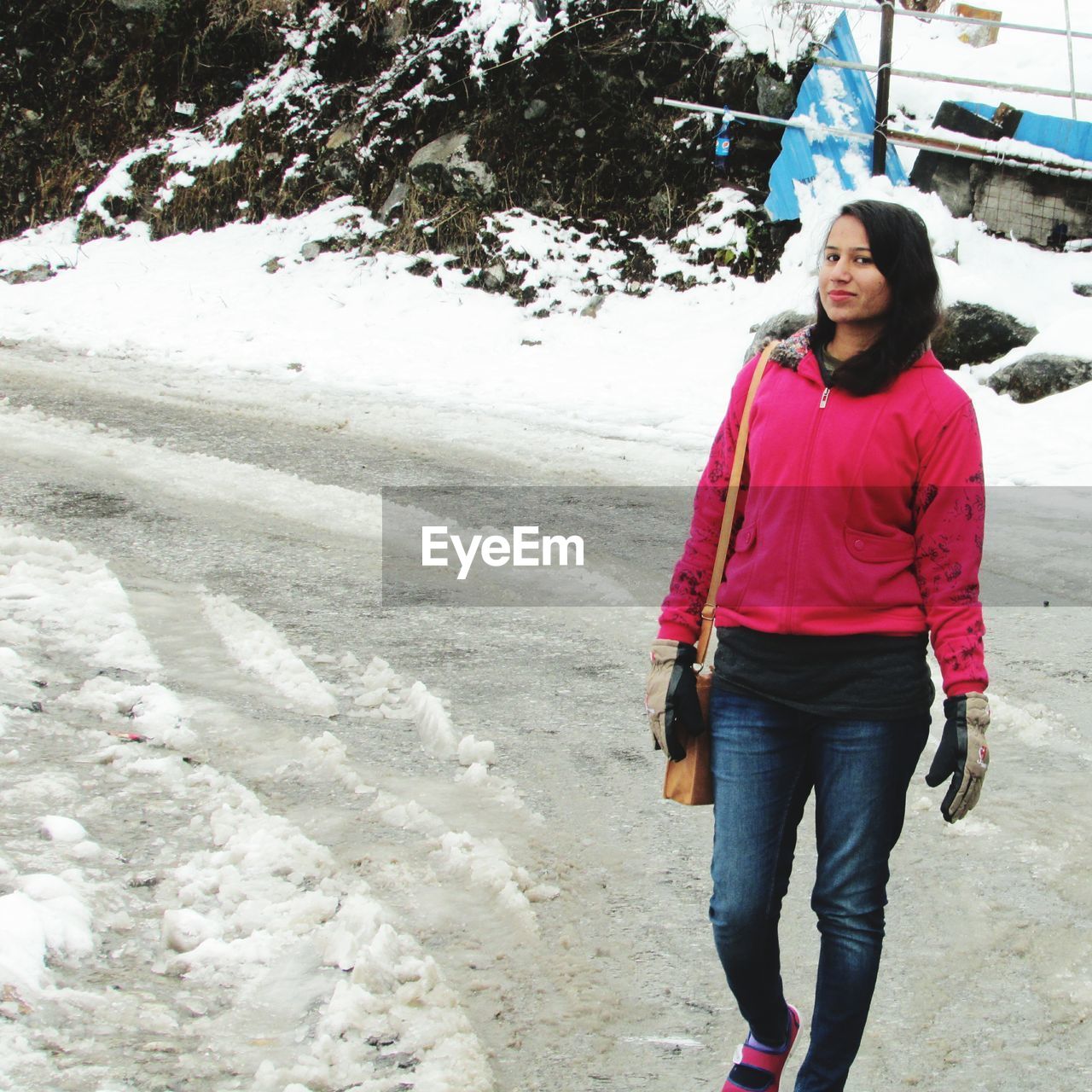 Full length of young woman walking on snow covered field