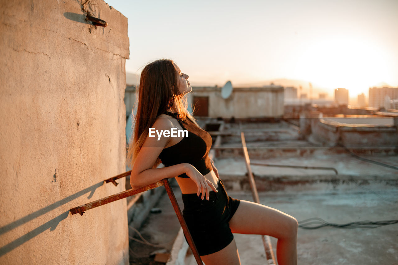 Side view of woman on terrace during sunset