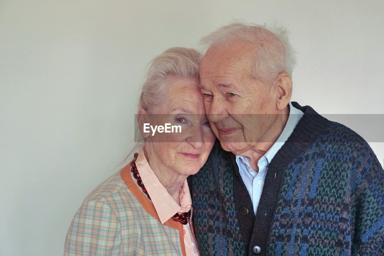 Senior couple hugging against wall