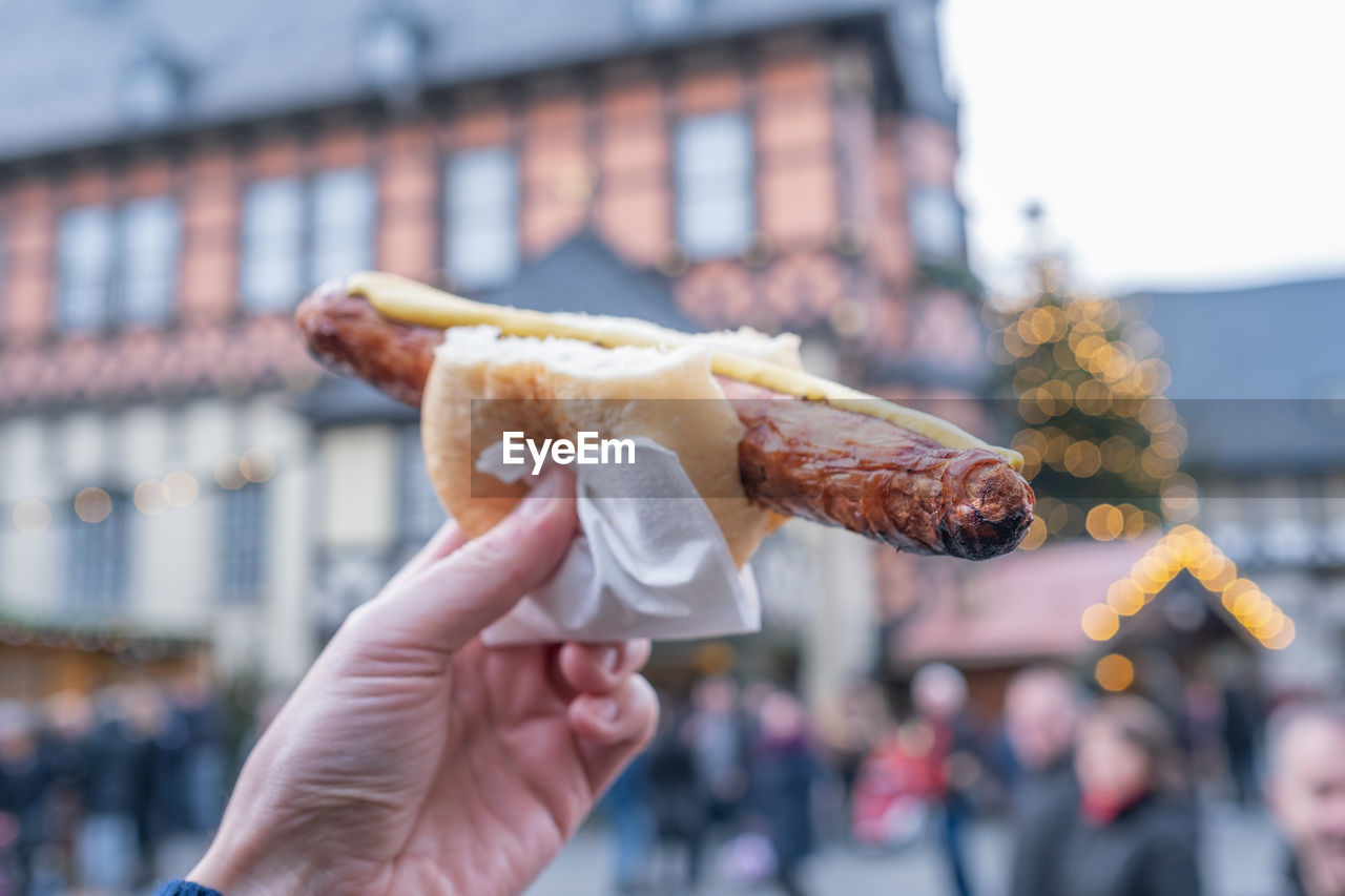 Close-up of hand holding bratwurst on christmas market