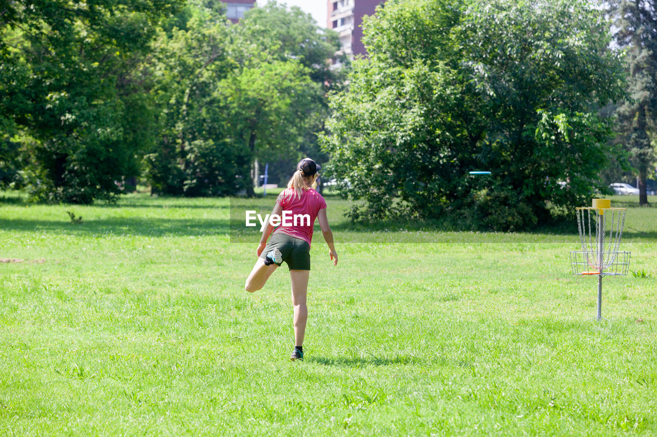 WOMAN RUNNING ON GRASS AGAINST TREES