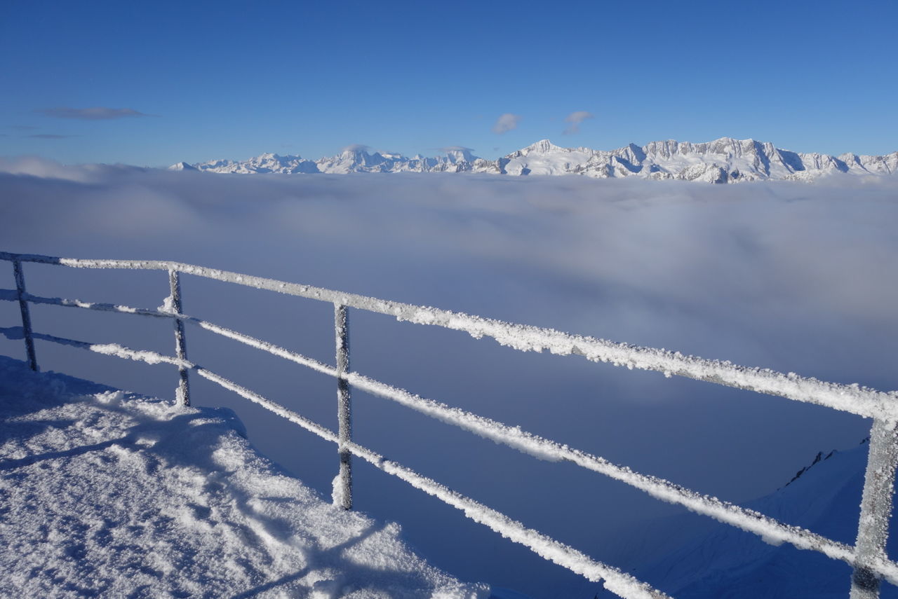 Snow covered fence with mountains in background
